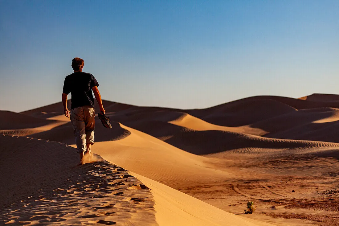 71456562–Africa-Morocco-Zagora-Sahara-Erg-Lehoudi-man-walking-over-sand-dune